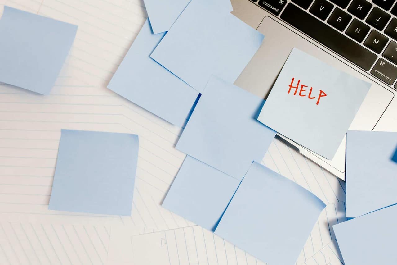 A cluttered workspace with sticky notes on a laptop, symbolizing overwhelm and the difference between being busy and productive