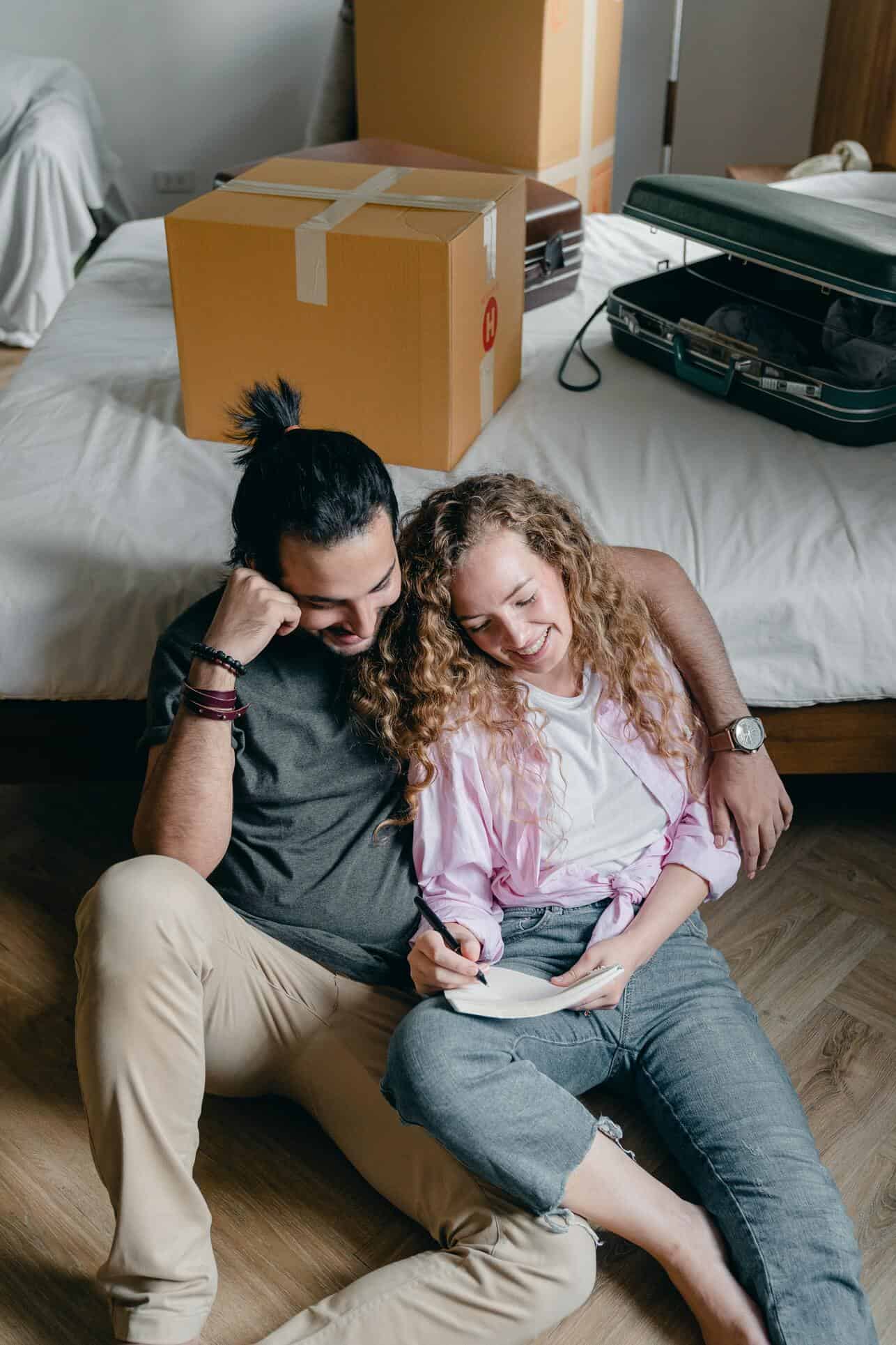 smiling couple sitting on the floor taking notes